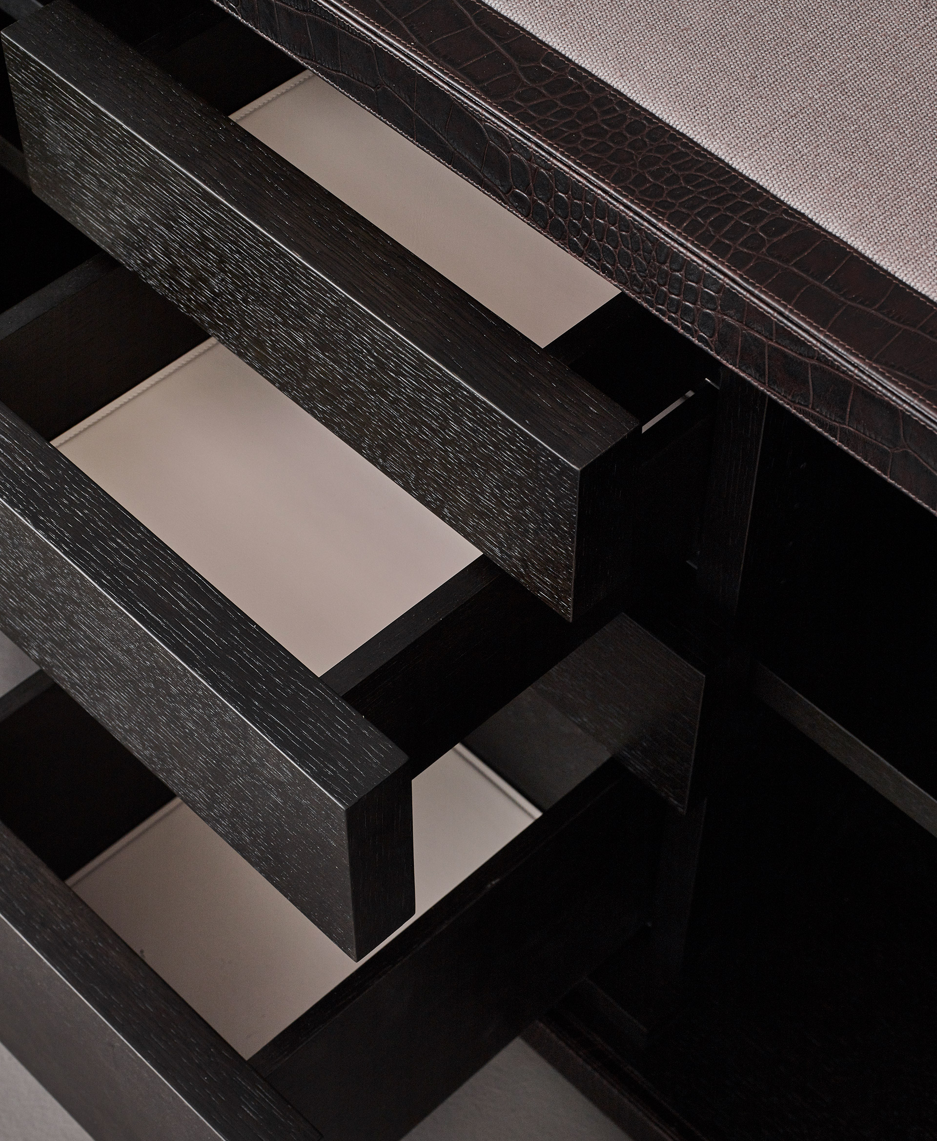 Drawers' detail of Future Voyager Atto II, a wooden cabinet covered in leather and fabric with handles and placemats in leather from Promemoria's catalogue | Promemoria