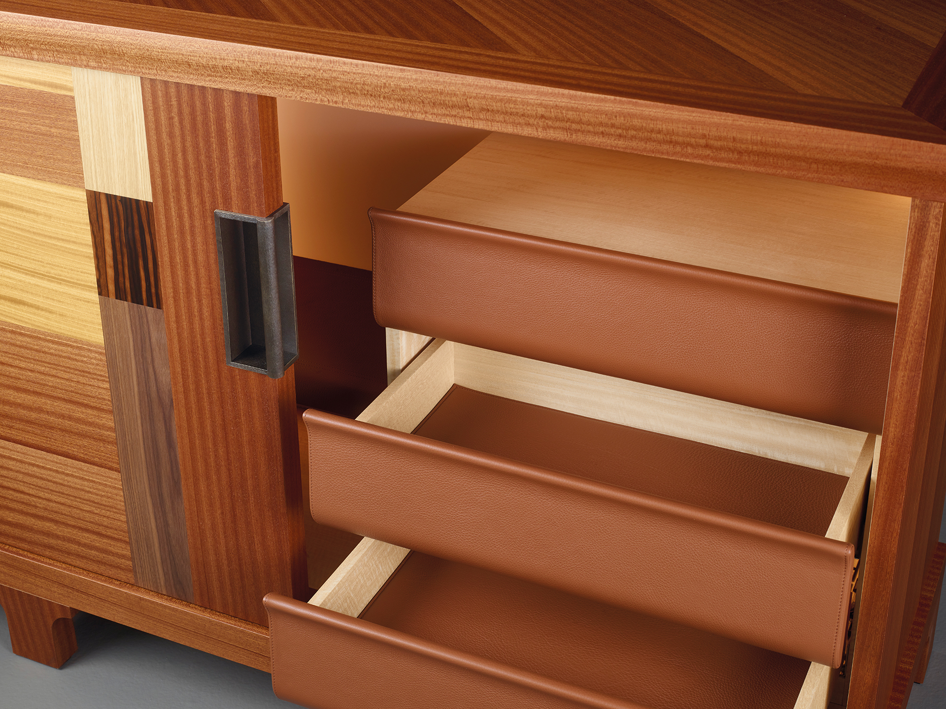 Interno di Oolong, mobile contenitore basso in legno con ante scorrevoli, frontali dei ripiani e cassetti in pelle e maniglie in bronzo, del catalogo di Promemoria | Promemoria