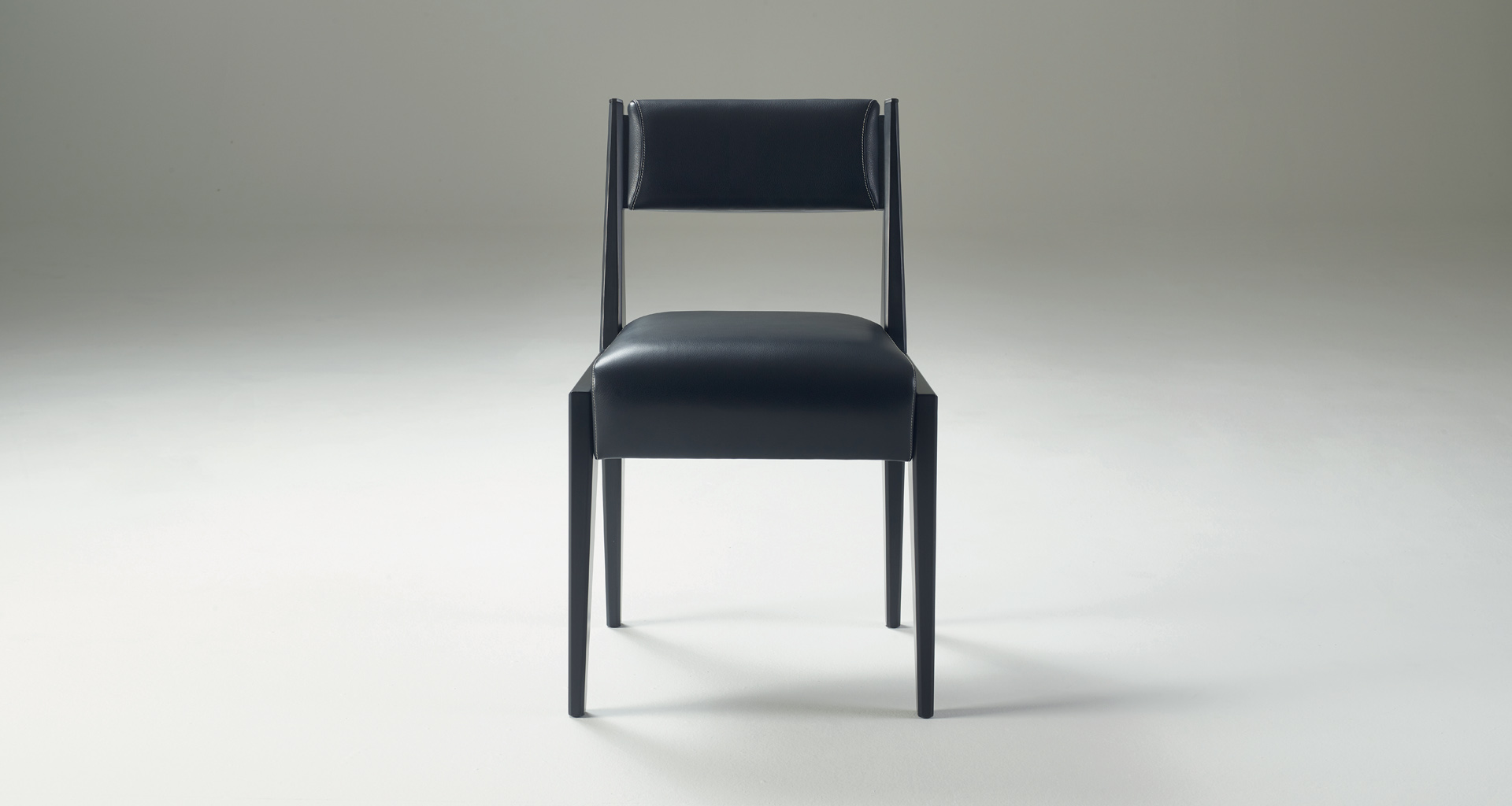 Iris is a wooden chair with bronze details and leather cushions, from Promemoria's Indigo Tales | Promemoria