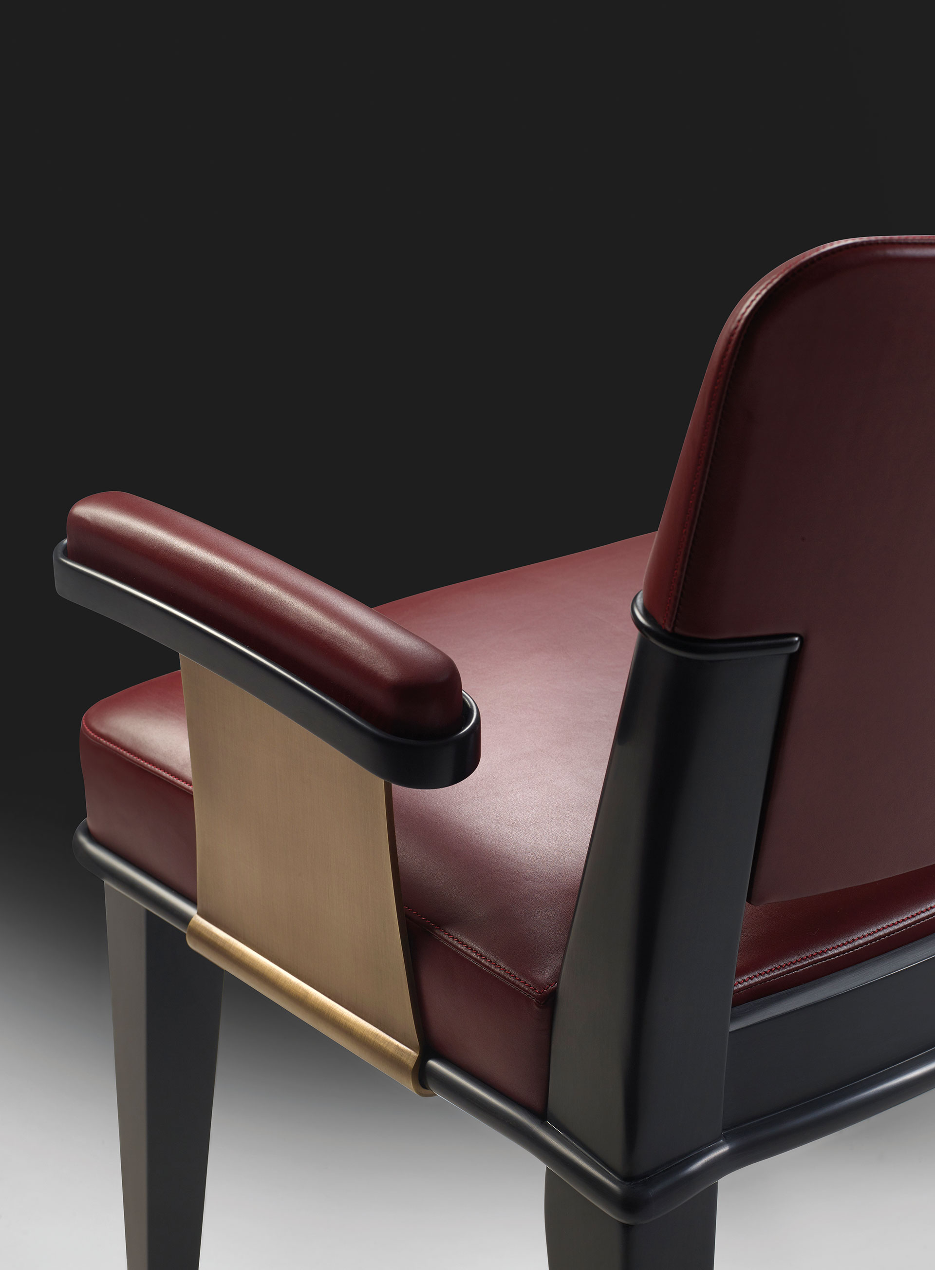 Detail of Vespertine, a wooden dining chair with leather seat and back and with armrests with bronze details, from Promemoria's Night Tales collection | Promemoria