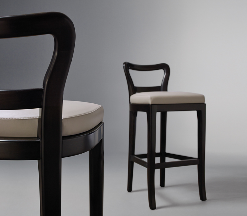 Sofia est une chaise de bar en bois avec assise revêtue de tissu ou de cuir. Ce meuble figure dans le catalogue Promemoria | Promemoria