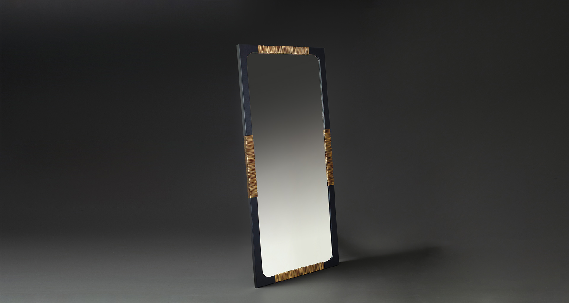 Belgrave is a mirror hpholtered in leather with details in bronze that belongs to Promemoria's The London Collection | Promemoria