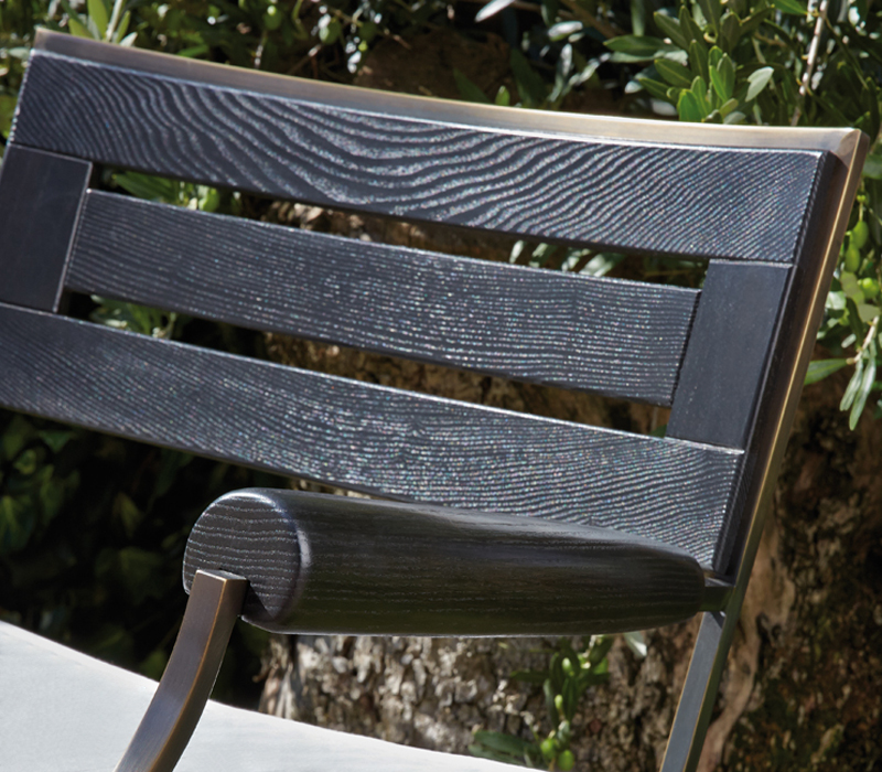 Detail of Cernobbio, a wooden and bronze armchair and pouf with fabric cushion, from Promemoria's outdoor catalogue | Promemoria