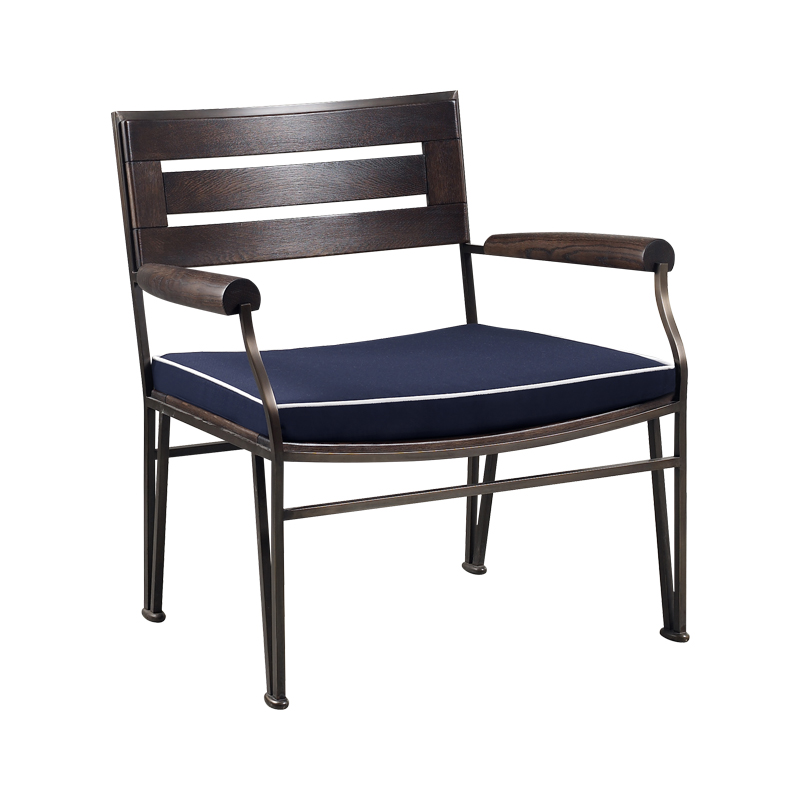 Cernobbio est un fauteuil de jardin, accompagné de son pouf, en bronze et en bois, avec un coussin en tissu. Ce meuble figure dans le catalogue de mobilier de jardin Promemoria | Promemoria