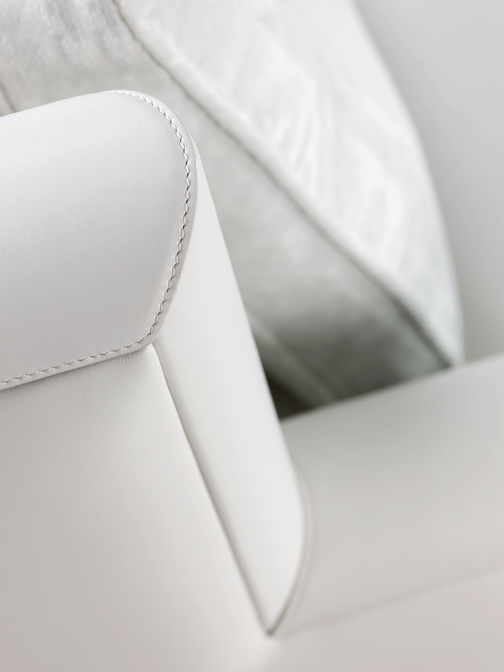 Detail of Ginevra, a wooden armchair covered in leather or fabric with bronze feet, from Promemoria's catalogue | Promemoria