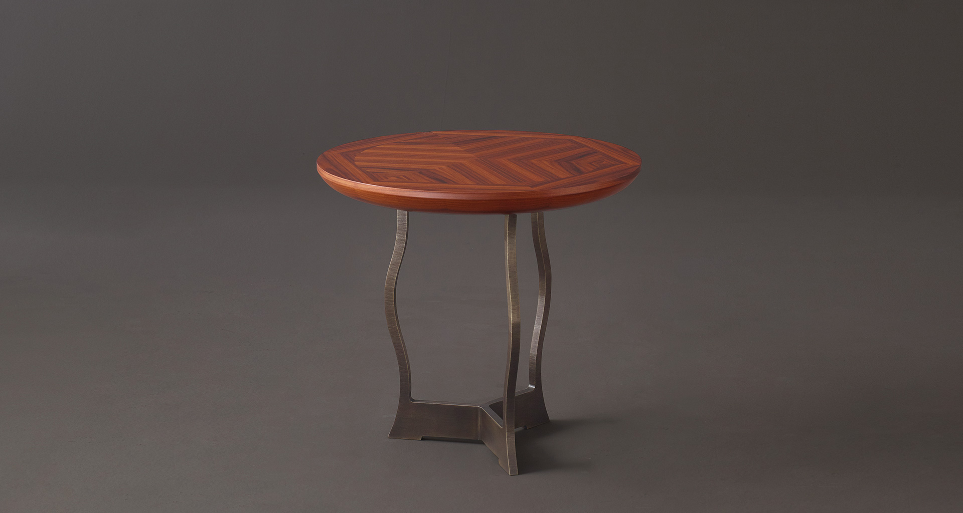 Erasmo is a circular bronze small table with wooden or leather top, from Promemoria's catalogue | Promemoria